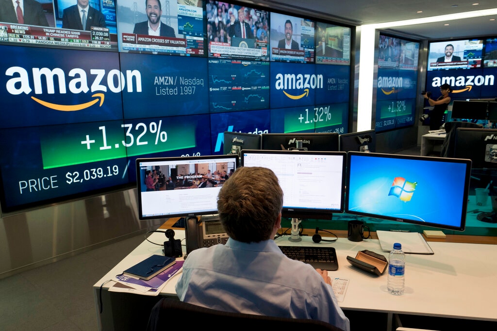 FILE- In this Sept. 4, 2018, file photo a Nasdaq employee monitors market activity in New York, with Amazon's logo on display in the background. The bull market in stocks started with the U.S. still reeling from the Great Recession in March 2009. The bull turns 10 this weekend, having survived threats such as a debt crisis in Europe (2011), a slowdown in the Chinese economy (2015-2016), and fears of inflation and rising interest rates in the U.S. (AP Photo/Mark Lennihan, File)