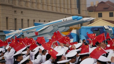 Chinese People's Liberation Army (PLA) Navy soldiers wave Chinese flags next to a model of a military vehicle carrying anti-ship missiles, during an event marking the 70th anniversary of the founding of Chinese People's Liberation Army Navy on April 23, at the navy museum in Qingdao, Shandong province, China April 13, 2019. Picture taken April 13, 2019. REUTERS/Stringer