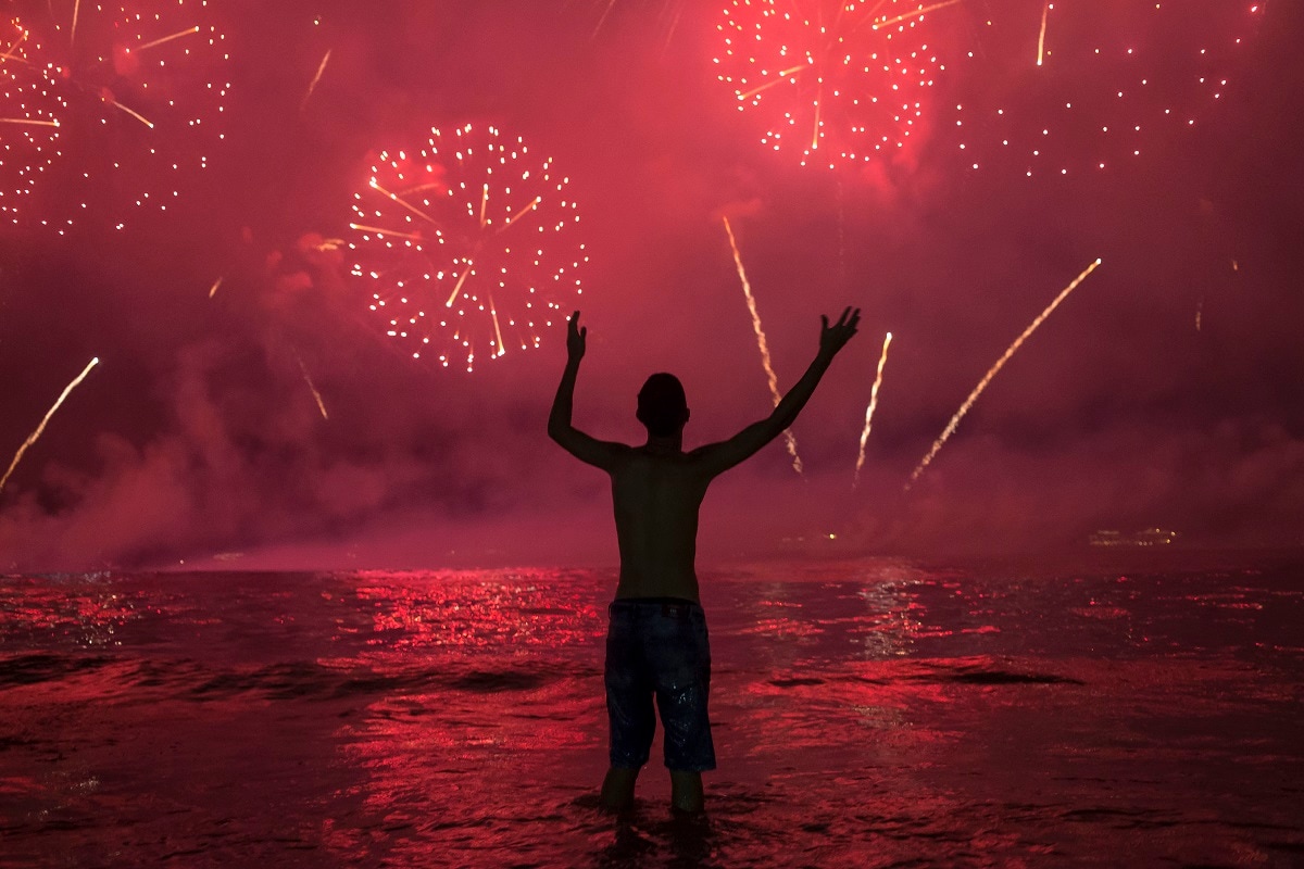 A man watches fireworks exploding over Copacabana Beach during the New Year's celebrations, in Rio de Janeiro, Brazil, Wednesday, Jan. 1, 2020. From Australia to Brazil, people gathered to ring in the new year with fireworks and musical celebrations. (AP Photo/Bruna Prado)