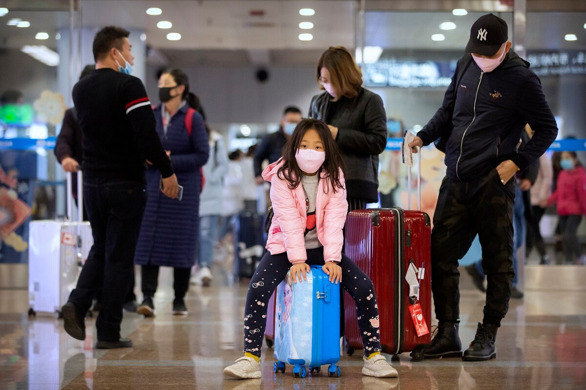Travelers wear face masks as they stand in the arrivals area at Beijing Capital International Airport in Beijing, Thursday, Jan. 23, 2020. China closed off a city of more than 11 million people Thursday, halting transportation and warning against public gatherings, to try to stop the spread of a deadly new virus that has sickened hundreds and spread to other cities and countries in the Lunar New Year travel rush. (AP Photo/Mark Schiefelbein)
