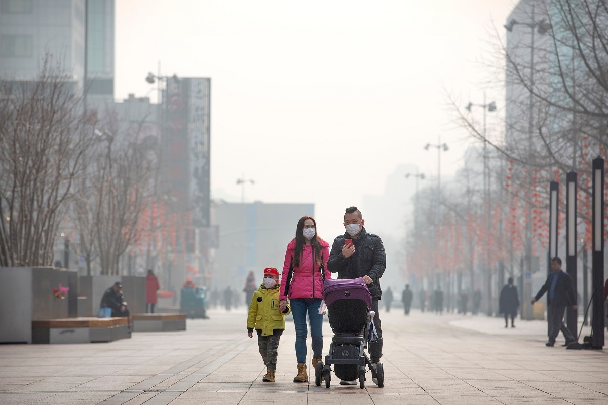 In this Tuesday, Jan. 28, 2020 photo, a family wearing face masks walk along a normally busy pedestrian shopping street in Beijing. Fears of a virus outbreak have kept many indoors and at home in China's capital. Cultural landmarks such as the Great Wall and Forbidden City have closed their doors to visitors, nearly deserted shopping malls have reduced their operating hours, and restaurants that remain open draw just a handful of customers. (AP Photo/Mark Schiefelbein)