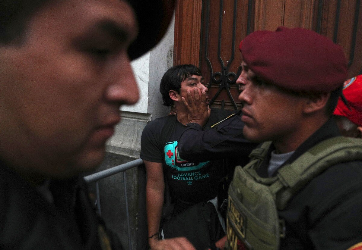 A supporter of opposition leader Keiko Fujimori, the daughter of Peru's former President Alberto Fujimori, is held back by police officers outside a courtroom in Lima, Peru, Tuesday, Jan. 28, 2020. A Peruvian judge ordered 15 months of preventive detention for Keiko Fujimori while she is investigated for alleged money laundering related to the Brazilian construction company Odebrecht. (AP Photo/Martin Mejia)