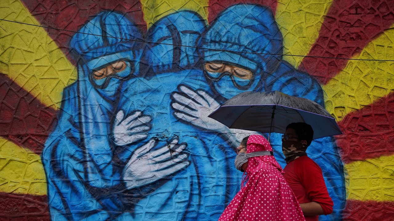 A woman wearing a protective face mask walks past a mural on a street, amidst the spread of the coronavirus disease (COVID-19). (Reuters)