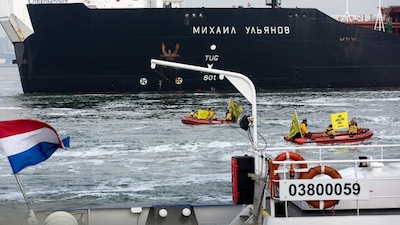 Members of Greenpeace sail past the Russian oil tanker Mikhail Ulyanov in the harbour of Rotterdam (Image: Reuters)
