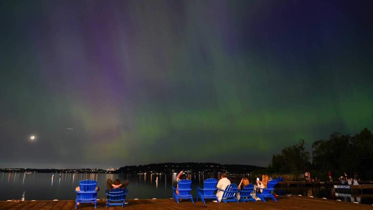 Northern Lights in Washington, US | People take photos of the Northern Lights, or Aurora Borealis, as they glow over Lake Washington, in Renton, Wash., on Friday evening, May 10, 2024. (Image: AP Photo/Lindsey Wasson)