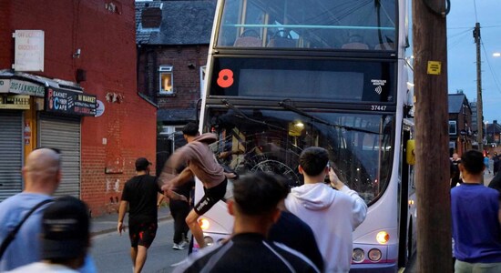 A man kicks a bus during unrest in Harehills, Leeds, Britain, July 18, 2024 in this still image obtained from social media video. @robin_singh via Instagram/via REUTERS THIS IMAGE HAS BEEN SUPPLIED BY A THIRD PARTY. MANDATORY CREDIT