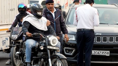 A traffic police personnel stops a motorcyclist to check the Pollution Under Control (PUC) certificate of his bike, in New Delhi, Wednesday, Nov. 20, 2024. (PTI Photo)(