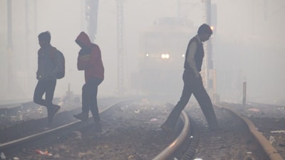 People cross railway tracks amid a dense fog, in Kanpur, Tuesday, Dec. 17, 2024. (PTI Photo) 