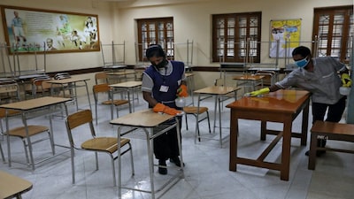 Workers wearing protective face masks disinfect chairs and tables inside an examination centre ahead of the National Eligibility cum Entrance Test (NEET), amidst the spread of the coronavirus disease (COVID-19), in Kolkata, India, September 10, 2020. REUTERS