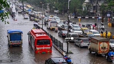 Commuters stuck in traffic as they wade through a flooded streets after heavy rain showers in Mumbai on September 28, 2025.