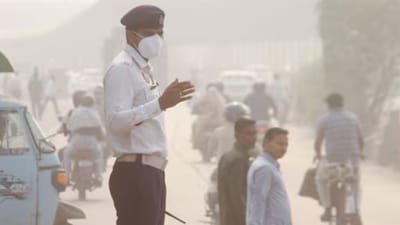 A traffic policeman wears a mask as he manages traffic amid low visibility after air quality deteriorated across northern India, in Gurugram. (PTI Image) 