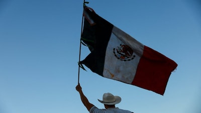 A protester holds a Mexican flag during a demonstration against insecurity and corruption in the country, as well as over the recent killing of Uruapan mayor Carlos Manzo, in Ciudad Juarez, Mexico, November 15, 2025. REUTERS/Jose Luis Gonzalez