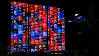 A window cleaner works next to Japan's Nikkei stock prices quotation board at a building in Tokyo, Japan February 19, 2024. REUTERS/Issei Kato