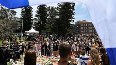 People gather next to a flower tribute near Bondi Pavilion following a shooting incident at Bondi Beach in Sydney, Australia, December 15, 2025. REUTERS/Flavio Brancaleone
