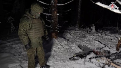 A Russian service member stands next to the remains of a drone, which, according to the Russian Defence Ministry, was downed during the repelling of an alleged Ukrainian attack on the Russian presidential residence in the Novgorod Region, in an unknown location in Russia, in this still image from a video released December 31, 2025. Russian Defence Ministry/Handout via REUTERS
