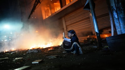 A girl rescues books from a shop near the premises of the Prothom Alo daily newspaper which was set on fire by angry protesters after news reached the country from Singapore of the death of a prominent activist Sharif Osman Hadi, in Dhaka, Bangladesh, Friday, Dec. 19, 2025. (AP Photo/Mahmud Hossain Opu)