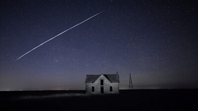 FILE - In this long exposure photo, a string of SpaceX StarLink satellites passes over an old stone house near Florence, Kan., on May 6, 2021. (AP Photo/Reed Hoffmann, File)