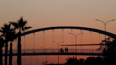People are silhouetted as they cross a pedestrian bridge during sunset hours, in Islamabad, Pakistan (Reuters)