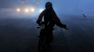  A man rides a two-wheeler amid dense fog on a winter morning, at Mayur Vihar area, in New Delhi, Saturday, Dec. 20, 2025. Visibility plunged across parts of Delhi on Saturday morning, with buildings and flyovers fading into a grey blur amid dense fog, as the capital�s AQI edged closer to the �severe� category at 384. (PTI Photo/Ravi Choudhary