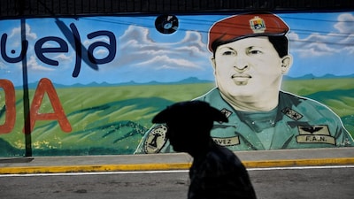 A member of the Bolivarian Militia is silhouetted against a mural with the image of Venezuela's late President Hugo Chavez, during a civic-military training, amid rising tensions with the U.S., in Caracas, Venezuela November 15, 2025. REUTERS/Maxwell Briceno