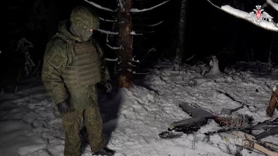 FILE PHOTO: A Russian service member stands next to the remains of a drone, which, according to the Russian Defence Ministry, was downed during the repelling of an alleged Ukrainian attack on the Russian presidential residence in the Novgorod Region, in an unknown location in Russia, in this still image from a video released December 31, 2025. Russian Defence Ministry/Handout via REUTERS/File Photo