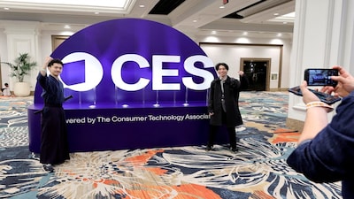 FILE PHOTO: Attendees pose by a CES sign before CES Unveiled at CES 2026, an annual consumer electronics trade show, in Las Vegas, Nevada, U.S. January 4, 2026.  REUTERS/Steve Marcus/File Photo