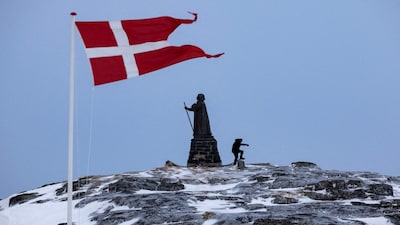 FILE PHOTO: A man walks as Danish flag flutters next to Hans Egede Statue in Nuuk, Greenland, March 9, 2025. REUTERS/Marko Djurica/File Photo