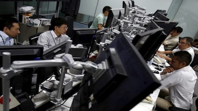 FILE PHOTO: Employees of a foreign exchange trading company work in front of monitors in Tokyo August 26, 2015.  REUTERS/Yuya Shino/File Photo