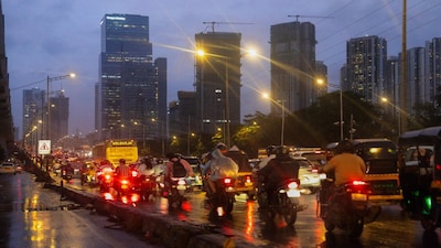 A Mumbai monsoon road, slick with reflections, framed by a looming urban backdrop.