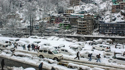 People make their way through a snow-covered road after fresh snowfall, at Manali in Kullu district, Himachal Pradesh. (PTI)