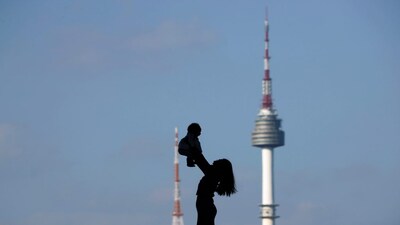 A woman holding up her baby is silhouetted against the backdrop of N Seoul Tower, commonly known as Namsan Tower, in Seoul, South Korea, October 2, 2018.   REUTERS/Kim Hong-Ji