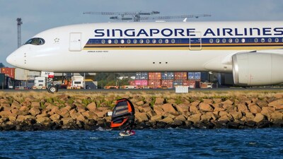 FILE - A man wing foils on Botany Bay as a Singapore Airlines passenger jet taxis after landing at Sydney Airport in Australia, Sept. 5, 2022. (AP Photo/Mark Baker, File)