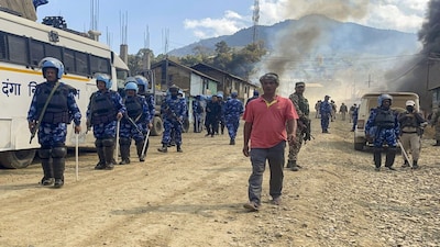 Ukhrul: Security personnel gather as smoke billows after armed miscreants allegedly set fire to houses, at Litan Sareikhong village, in Ukhrul district of Manipur, Monday, Feb. 9, 2026. Violence first started in the area on Saturday night after a Tangkhul Naga community member was allegedly assaulted by seven to eight persons at Litan village. (PTI Photo)(PTI02_09_2026_000363B)
