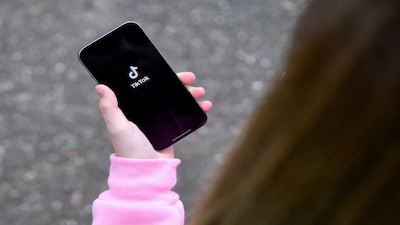 A teenager poses for a picture with a phone displaying the TikTok logo, in Bonn, Germany, February 20, 2026. REUTERS/Jana Rodenbusch