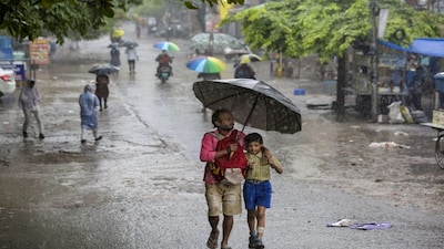 New Delhi: A man with a child makes his way amid heavy monsoon rain, in New Delhi, Tuesday, July 28, 2026. Parts of Delhi received rain with the India Meteorological Department (IMD) issuing an 'orange' alert for more rain at several places over the next few hours. (PTI Photo)(PTI07_28_2026_000061B)
