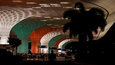 FILE PHOTO: File Photo: A man walks in front of the Chhatrapati Shivaji Maharaj International Airport, lit up in the colours of India's national flag on the eve of the 75th Independence Day in Mumbai, India, August 14, 2021. REUTERS/Francis Mascarenhas/File Photo/File Photo