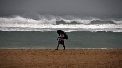 A man holds an umbrella as he walks along a beach during a rain shower in Odisha, India, July 16, 2015. India recorded above-average rains in June but forecasters have said the rains, critical for about half the nation's farmland that lacks irrigation facilities, would remain subdued in large parts of the country in the first half of July. REUTERS/Stringer