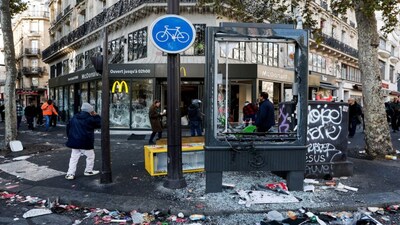People walk past the damaged window of a McDonald's, the day after clashes during a national day of demonstrations against the cost of living and rising fuel prices, in Paris, France, October 18, 2026. REUTERS/Benoit Tessier     TPX IMAGES OF THE DAY