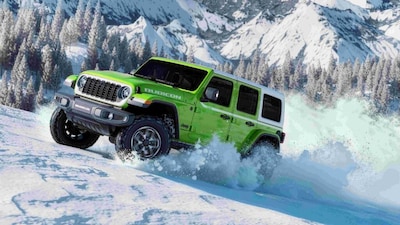 The Jeep Wrangler Rubicon Whitecap Edition drives through snow, showcasing its off-road capability.