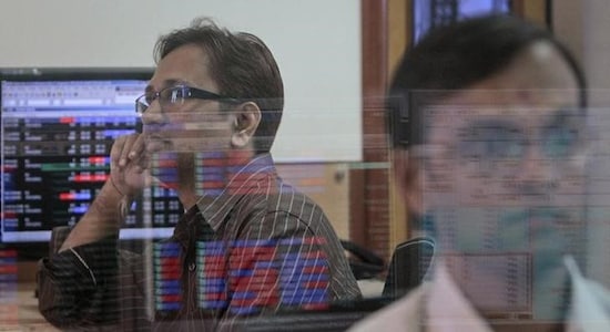 A broker watches a TV news channel as another monitors share prices at a brokerage firm in Mumbai stocks market bse nse