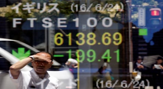 FILE PHOTO: A man is reflected in an electronic board showing Britain's FTSE 100 outside a brokerage in Tokyo, Japan, June 27, 2016. REUTERS/Toru Hanai/File Photo