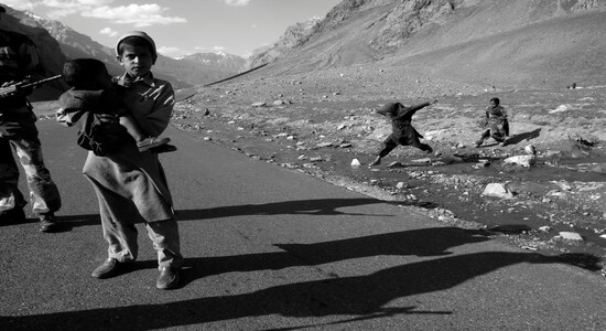 A Bakhrawal child holds an infant along the Meena bagh road in Kargil district. The life along the LoC is between the flying bullets and shells. The Bakhrawal tribe helped Indian intelligence agencies and the Indian army with vital inputs about intruders on the remote high hills.
