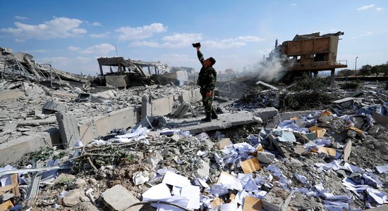 A Syrian soldier films the wreckage of the Syrian Scientific Research Center, which was attacked by U.S., British and French military strikes to punish President Bashar Assad for a suspected chemical attack against civilians, in the Damascus suburb of Barzeh, Syria, on April 14, 2018. (AP Photo/Hassan Ammar)