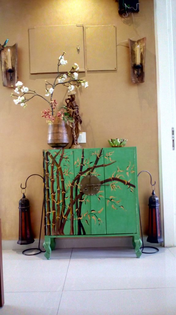 The green painted crockery cabinet has designs of bamboo shoots and leaves. A popular theme of artist Gama Lynn.