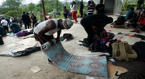 In this May 25, 2019 photo, a migrant from Cameroon rolls up his mattress in Bajo Chiquito, Darien province, Panama. The migrants wait about 10 days in Bajo Chiquito for a two hour boat trip to their next stop on their way north, the village of Peñitas. (AP Photo/Arnulfo Franco)
