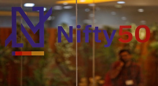 A man speaks on his mobile phone past a newly launched Nifty Indices logo inside the National Stock Exchange building in Mumbai