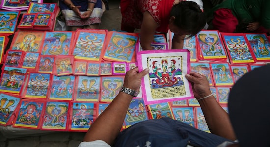 In this Aug. 4, 2019, photo, a Nepalese man checks a traditional painting displayed for sale at a market during Naag Panchami festival in Bhaktapur, Nepal. The art and tradition of Nepal’s Chitrakar families, who depicted gods and goddesses on temples, masks of Hindu deities and posters for various religious celebrations is dying because of mass machine printed posters and card-size pictures of gods that are cheaper and more popular. (AP Photo/Niranjan Shrestha) In this Aug. 4, 2019, photo, a Nepalese man checks a traditional painting displayed for sale at a market during Naag Panchami festival in Bhaktapur, Nepal. The art and tradition of Nepal’s Chitrakar families, who depicted gods and goddesses on temples, masks of Hindu deities and posters for various religious celebrations is dying because of mass machine printed posters and card-size pictures of gods that are cheaper and more popular. (AP Photo/Niranjan Shrestha)
