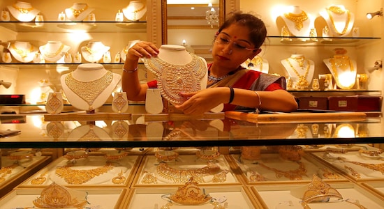 A saleswoman displays a gold necklace inside a jewellery showroom on the occasion of Akshaya Tritiya, a major gold buying festival, in Kolkata