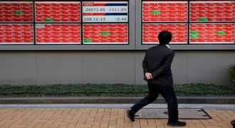 A man looks at an electronic board showing the Nikkei stock index outside a brokerage in Tokyo