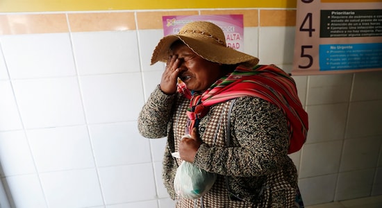 In this Tuesday, Nov. 19, 2019 photo, a woman who arrived in an ambulance with a man injured during clashes between security forces and supporters of former President Evo Morales cries at the Bolivian-Dutch Hospital, in El Alto, on the outskirts of La Paz, Bolivia. At least one person was killed when security forces launched an operation to supply gasoline from a major fuel plant that had been blockaded by Morales' backers. (AP Photo/Natacha Pisarenko)